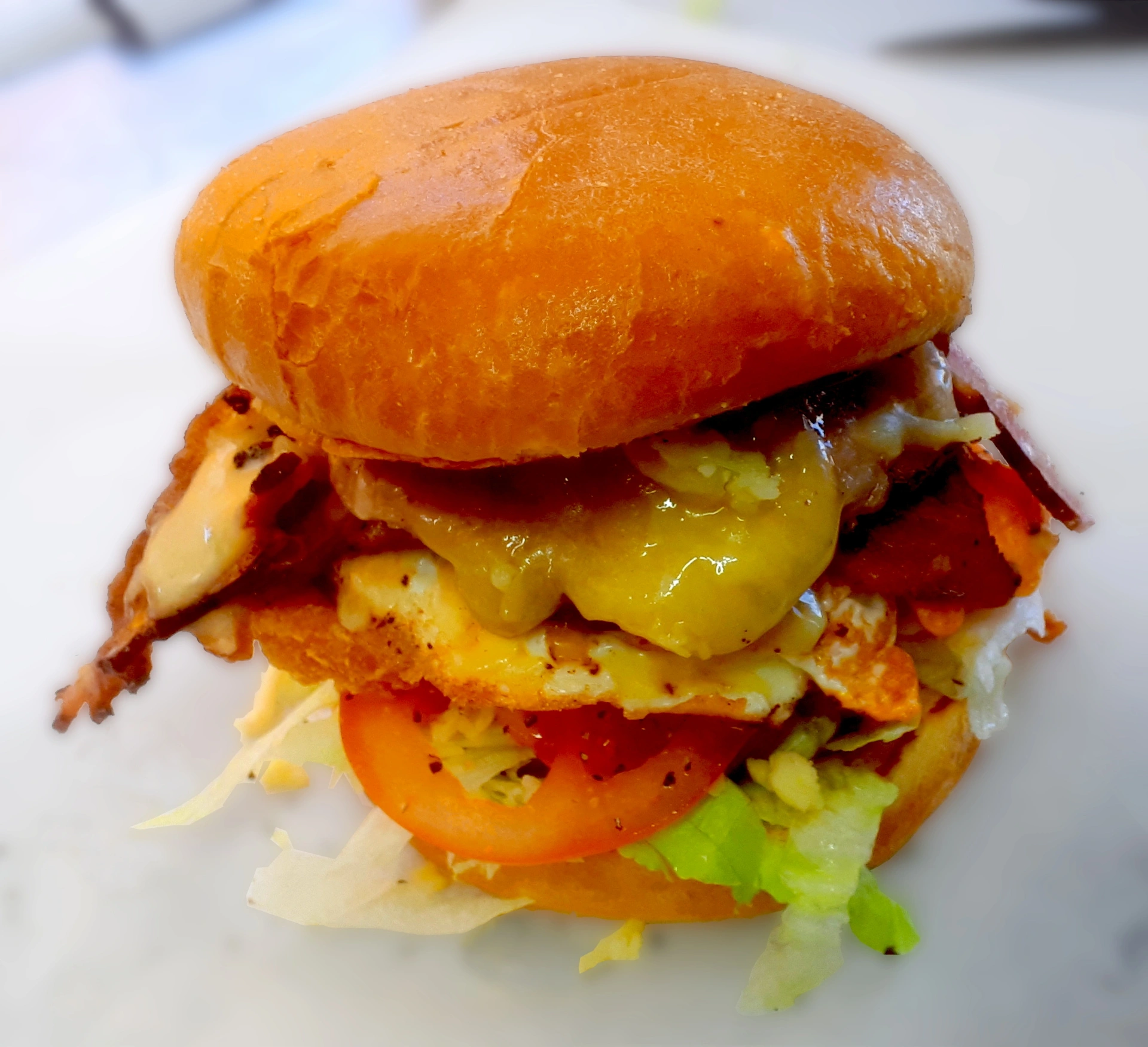 Bacon and egg burger with cheese, hash brown, lettuce and tomato