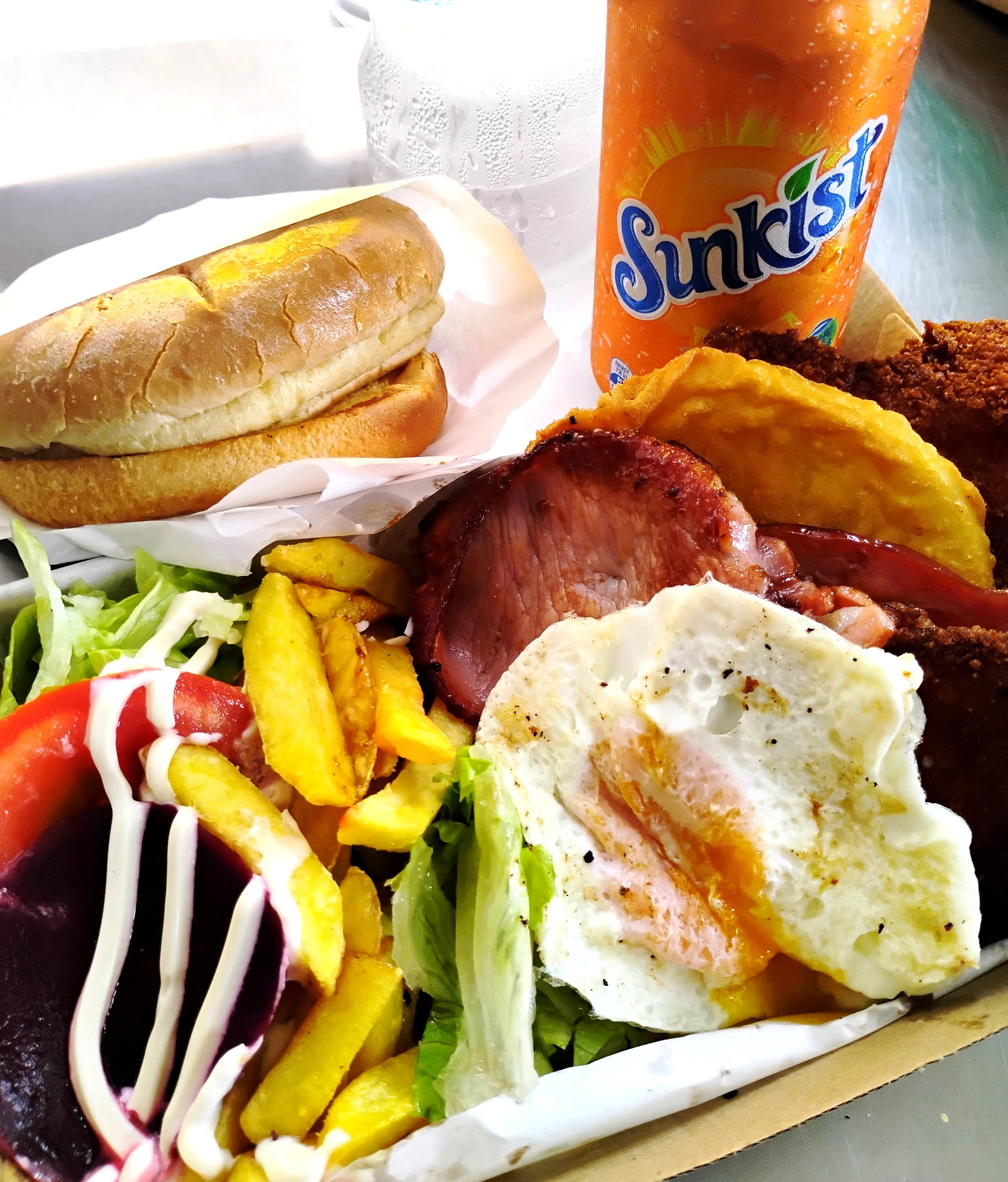 Open chicken schnitzel box with bacon, egg, chips and salad